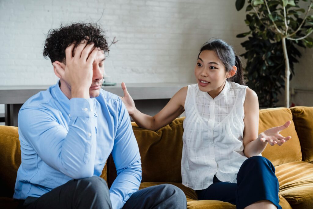 A couple having a serious conversation while sitting on a couch indoors.