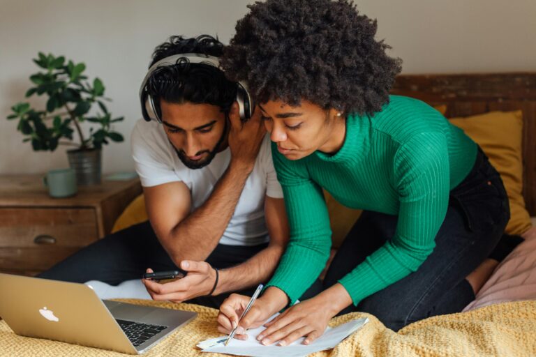 Young couple working together at home with a laptop and notes. Cozy indoor setting.