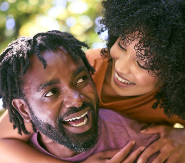 Loving Mid Adult Couple Outdoors In Summer Garden Or Countryside With Man Giving Woman Piggyback